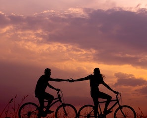 Ett par som cyklar mot en bakgrund av solnedgång